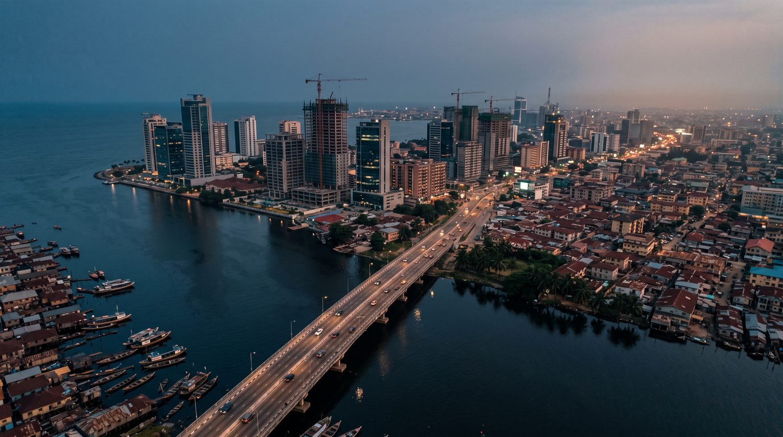 A wide aerial view of a modern African city skyline at dusk with construction cranes and infrastructure development visible, symbolising rapid economic growth